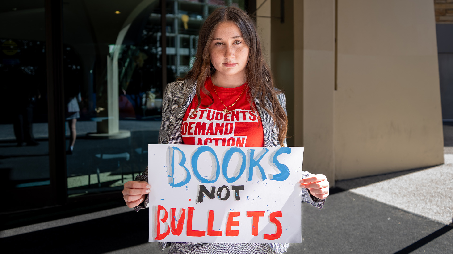 Picture of student holding a sign that says, "Books not Bullets"